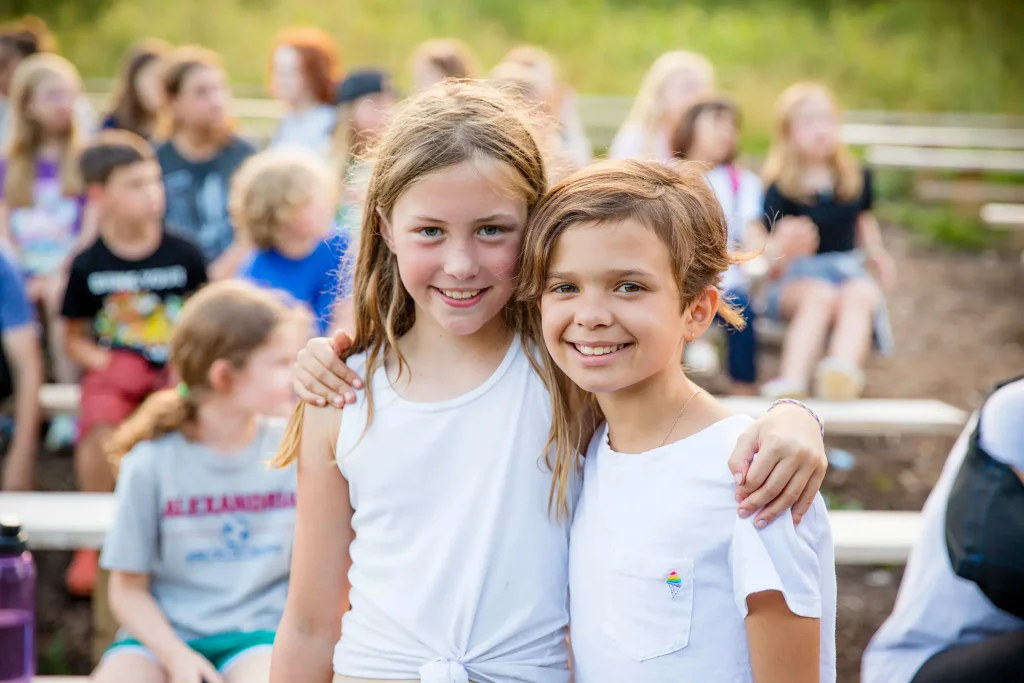 Two campers smiling, with arms around each other