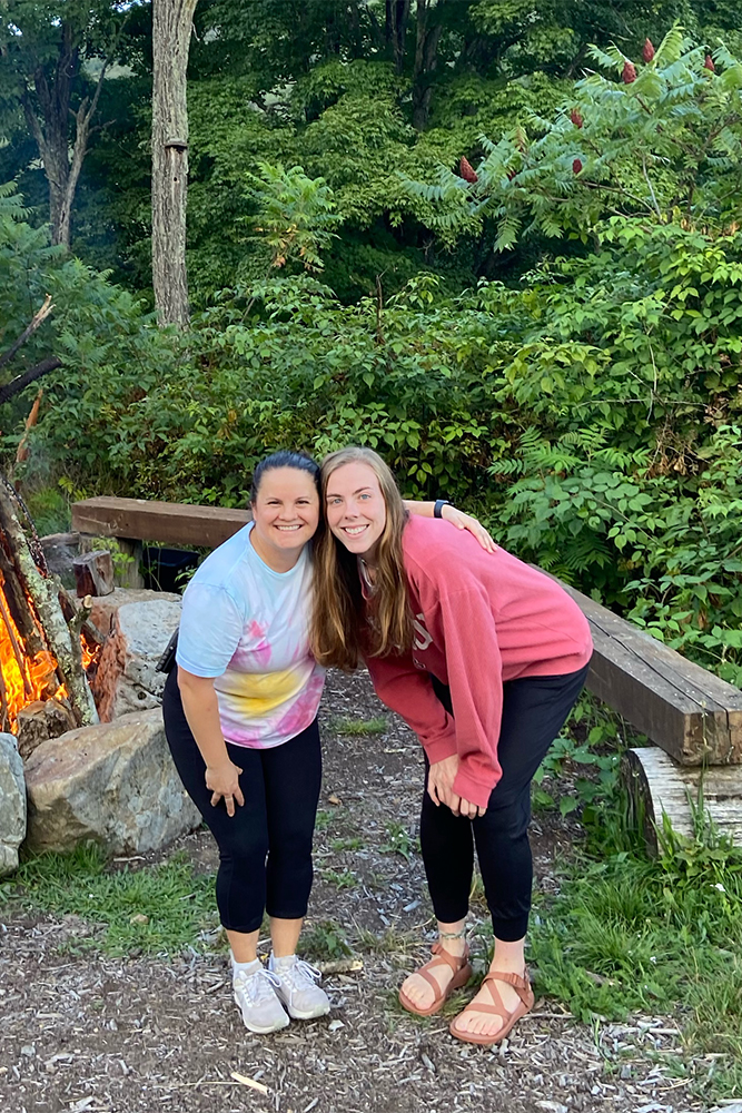 two women standing in front of a fire pit, enjoying a cozy evening outdoors